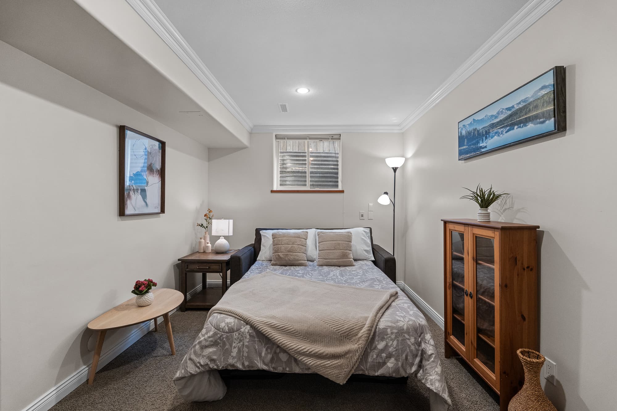 Secondary bedroom staged with layered bedding and reading lamp